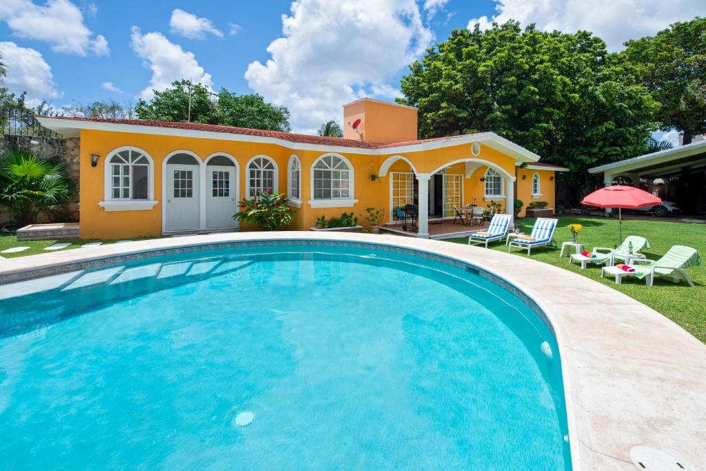 a villa with a swimming pool in front of a house at Orquideas Villas & Studios at Country House in Cancún