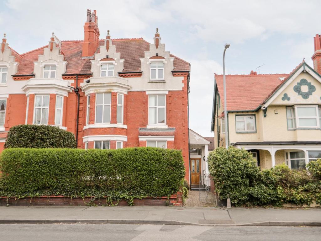 a large house with a hedge in front of it at 10 Carmen Sylva Road in Llandudno