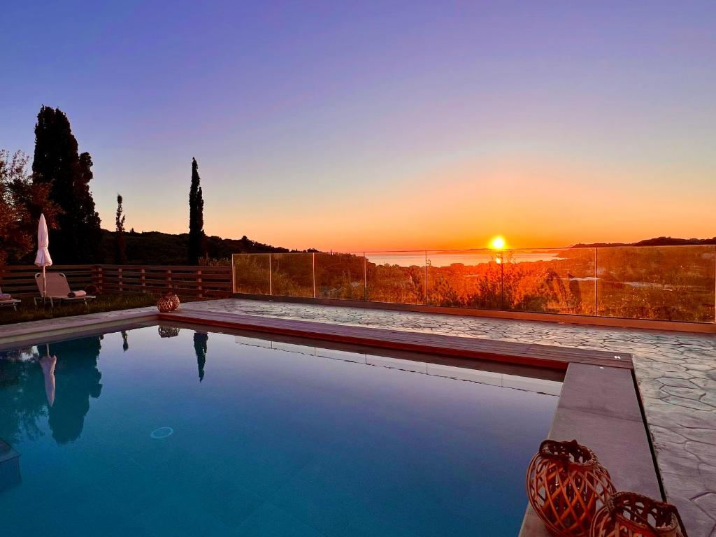 a swimming pool with a sunset in the background at Luxury Villa Makris with private heatable pool in Kavvadádes