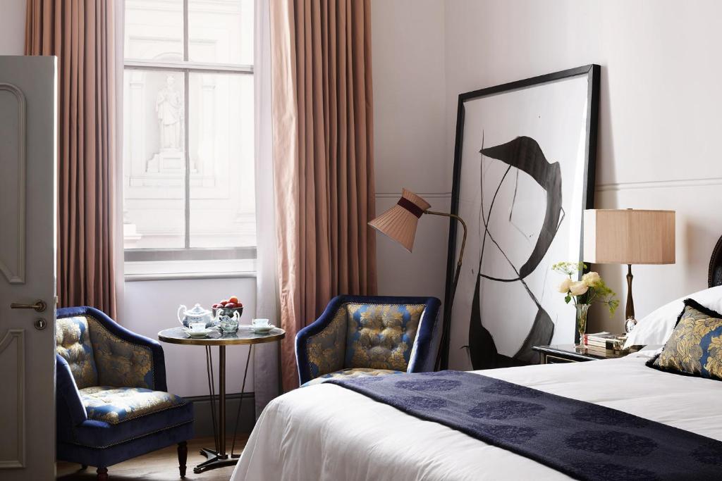 une chambre d'hôtel avec un lit et deux chaises dans l'établissement NoMad London, à Londres