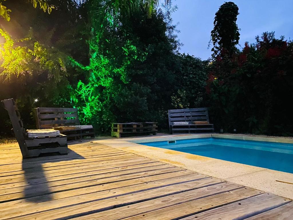 una piscina con due panche accanto a una terrazza in legno di CASA MIA bednbreakfast a Colonia del Sacramento