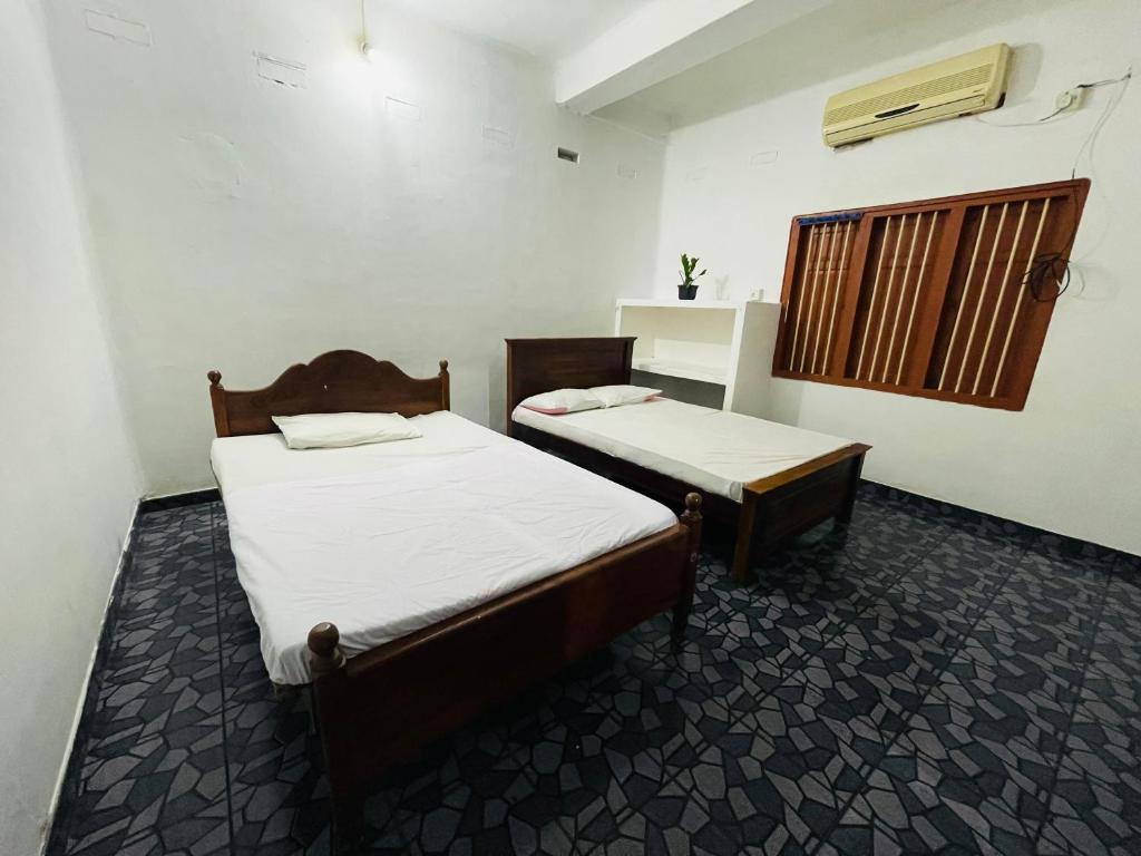 Zimmer mit 2 Betten und einem Fenster in der Unterkunft Jaffna RR Holiday Home Non AC in Jaffna