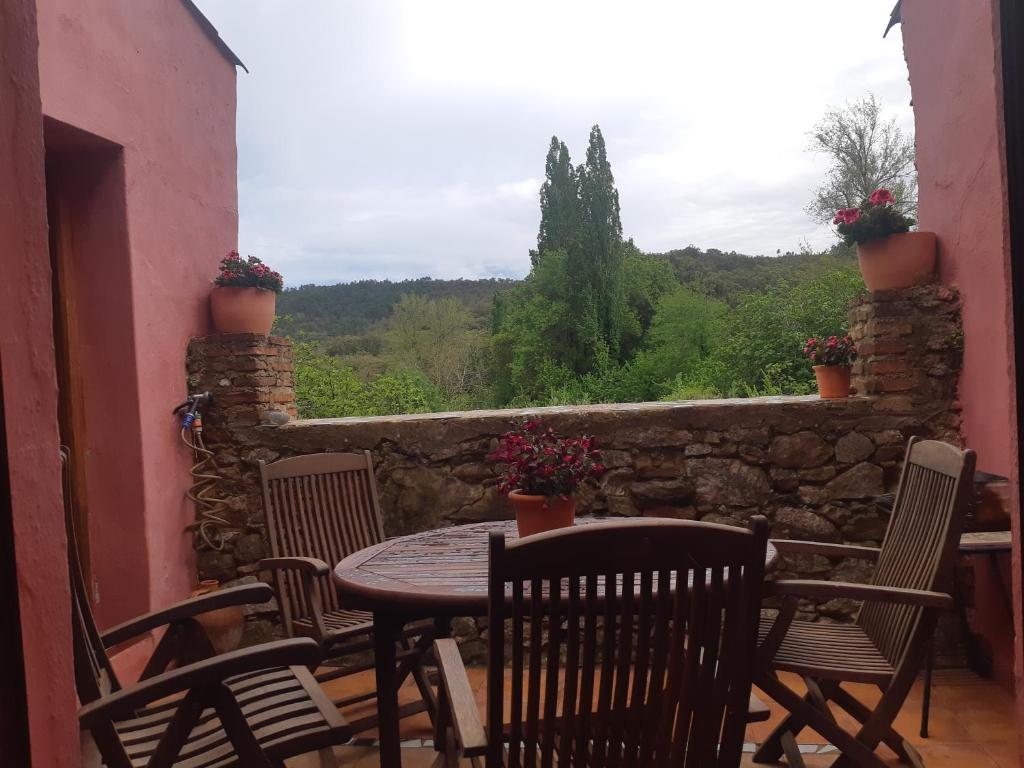 um pátio com uma mesa e cadeiras e uma parede de pedra em Bonita Casa Rural en la Sierra de Aracena em La Presa