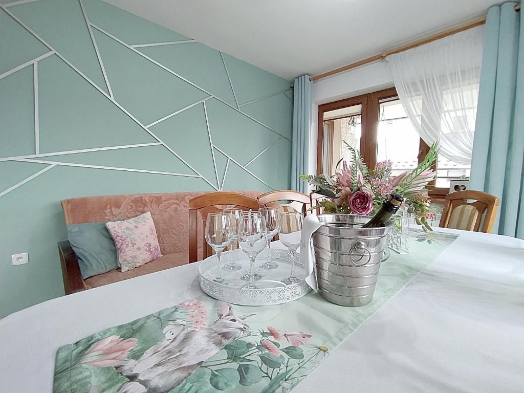 Olczański Dom في زاكوباني: طاولة غرفة الطعام مع نظارة والزهور عليها