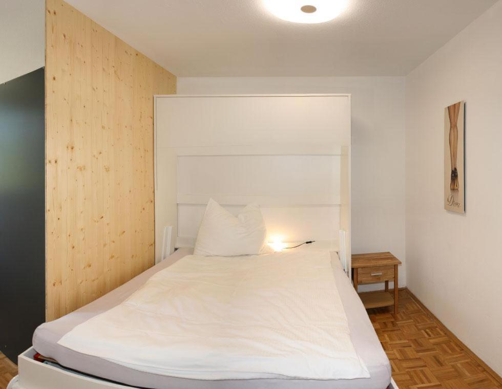 a bedroom with a large white bed with a wooden headboard at Ferienwohnung Sonnenschein in Bad Aussee