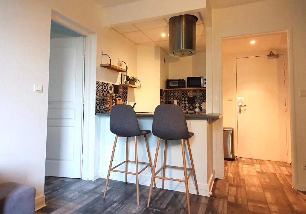 a kitchen with two bar stools in front of a counter at OISEAU DE PARADIS - 7 Min des Parcs Walt Disney- Arrivée autonome-Parking et Wifi gratuit- Proche commerces et restaurant Idéal pour les familles in Magny-le-Hongre