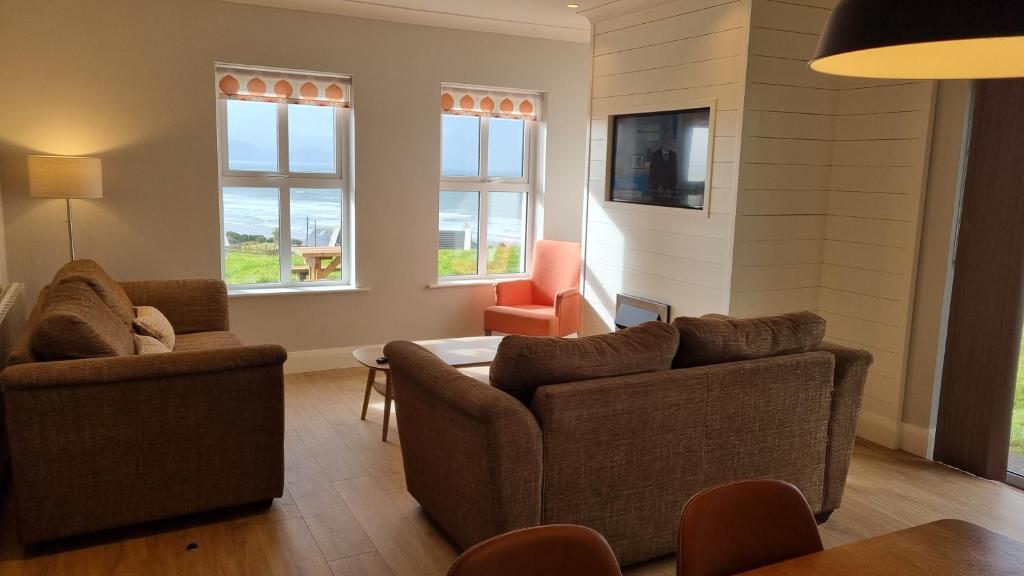 uma sala de estar com dois sofás e uma mesa e duas cadeiras em Inch Beach Cottages em Inch