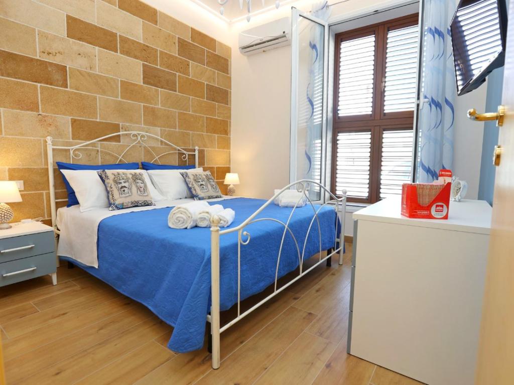 a bedroom with a blue bed and a brick wall at Casa vacanze - "O Tunnu" in Avola