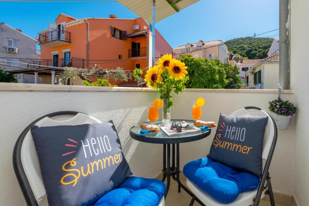 2 stoelen en een tafel op een balkon met zonnebloemen bij Apartman MatLuk1 in Dubrovnik