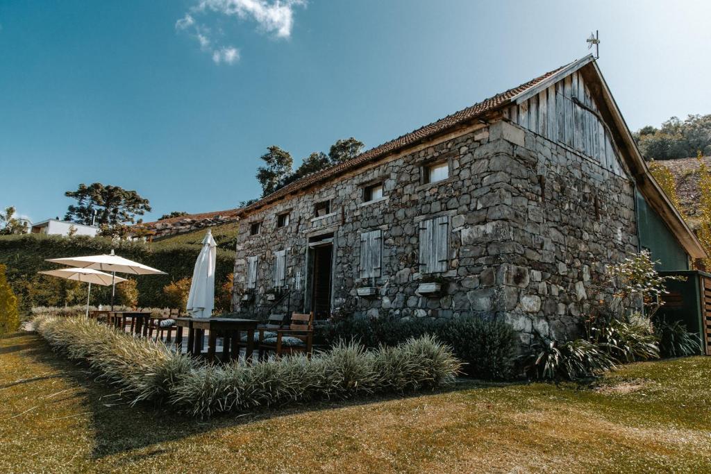 un vecchio edificio in pietra con ombrellone e tavoli di Pousada Cantelli a Bento Gonçalves