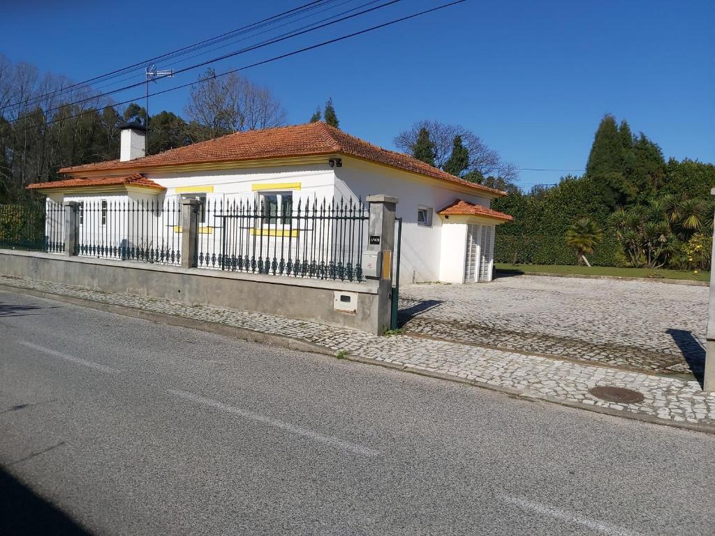 una casa bianca con una recinzione sul lato di una strada di T3 Cozy Old House with XL garden a Borralha