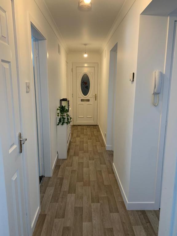 un pasillo con paredes blancas y suelo de madera en Dumfries Apartment en Dumfries