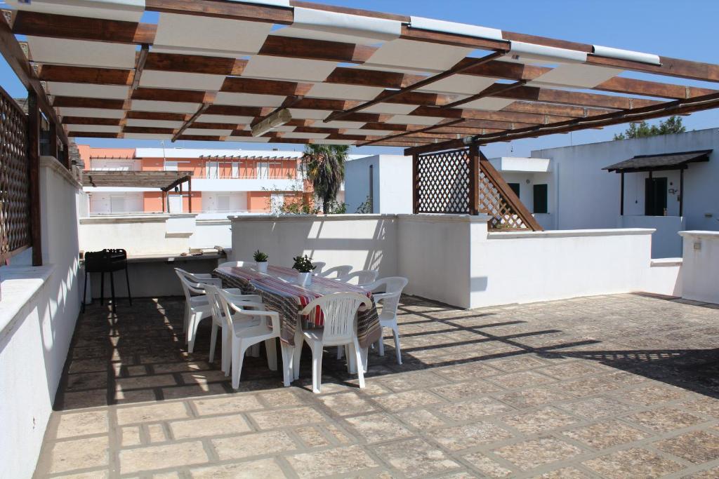 patio ze stołem i krzesłami pod pergolą w obiekcie Villetta Porto Selvaggio w mieście Nardò