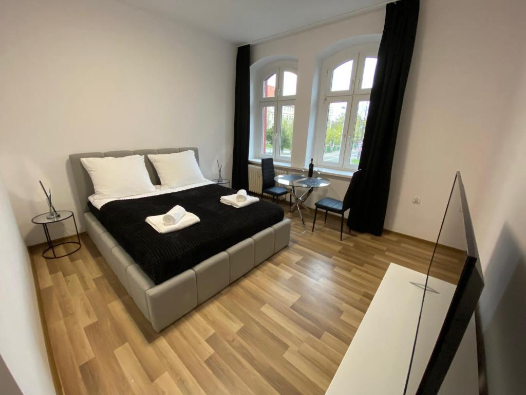 a bedroom with a bed and a table and windows at VIP Rooms Apartment in Toruń