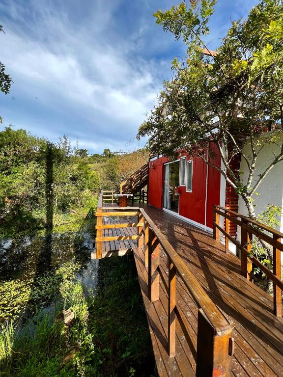 a red house on a wooden deck next to a river at Cabanas Avencal Frutas in Urubici