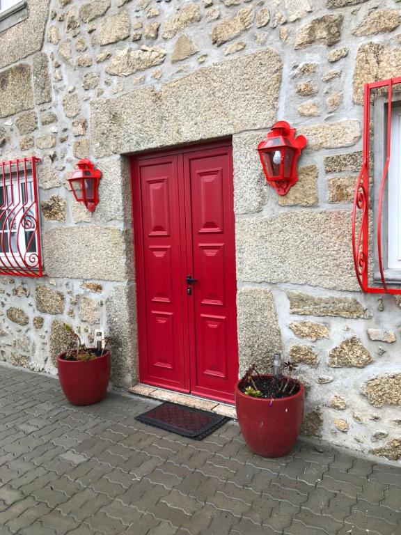 una puerta roja en el lateral de un edificio de piedra en Casa Dos Cabritos, en Melo