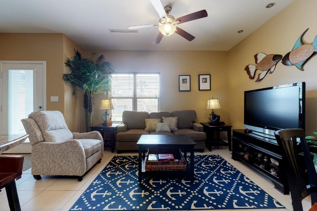 sala de estar con sofá y TV de pantalla plana en Kingfisher, en South Padre Island