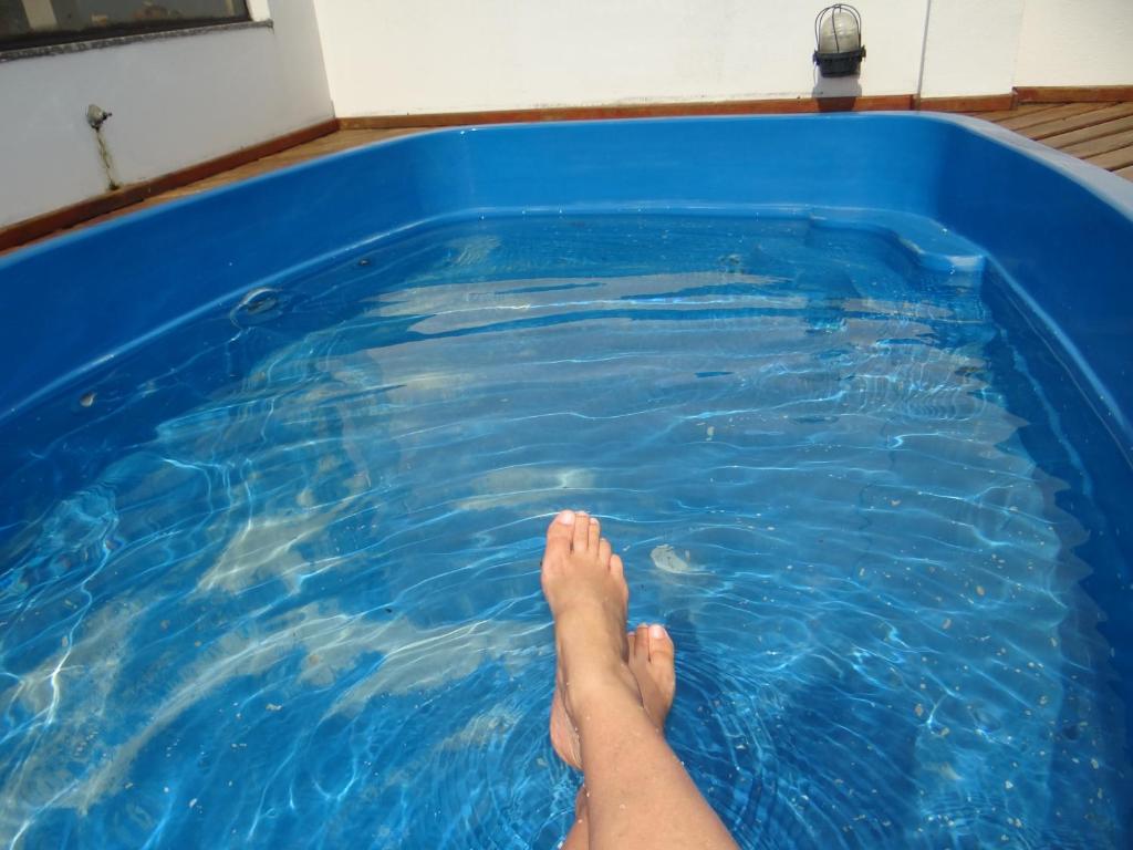 uma pessoa sentada numa piscina com os pés na água em Triplex Enseada Guarujá no Guarujá