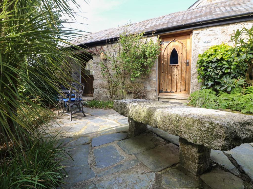 una panca in pietra di fronte a un edificio con porta in legno di Trevenning Chapel a Michaelstow