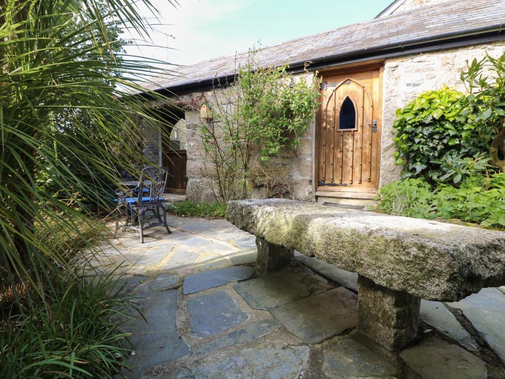 a stone bench in front of a building with a wooden door at Trevenning Chapel in Michaelstow