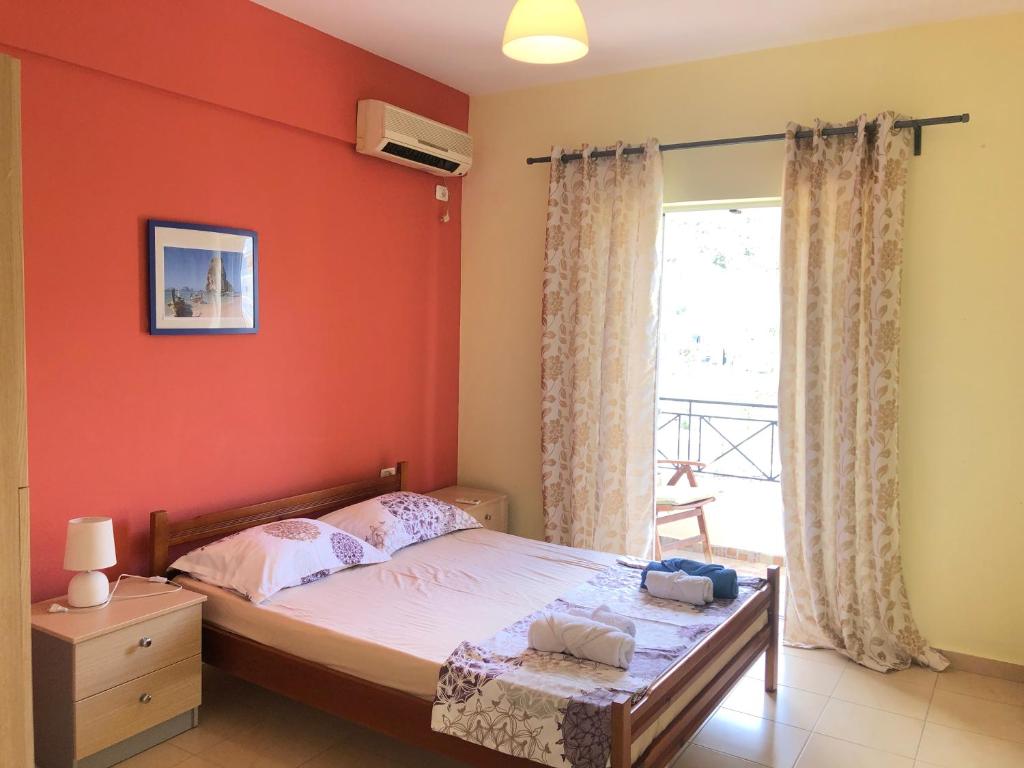 a bedroom with a bed with an orange wall at Veizi's Apartments in Himare