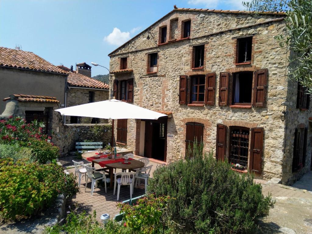 una mesa con sombrilla frente a un edificio en Les Ecuries, traditional stone farmhouse with pool en Marquixanes