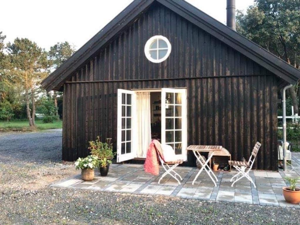 a black barn with chairs and a table in front of it at Country-living with a lovely view and own terrace, entrance and parking in Roskilde
