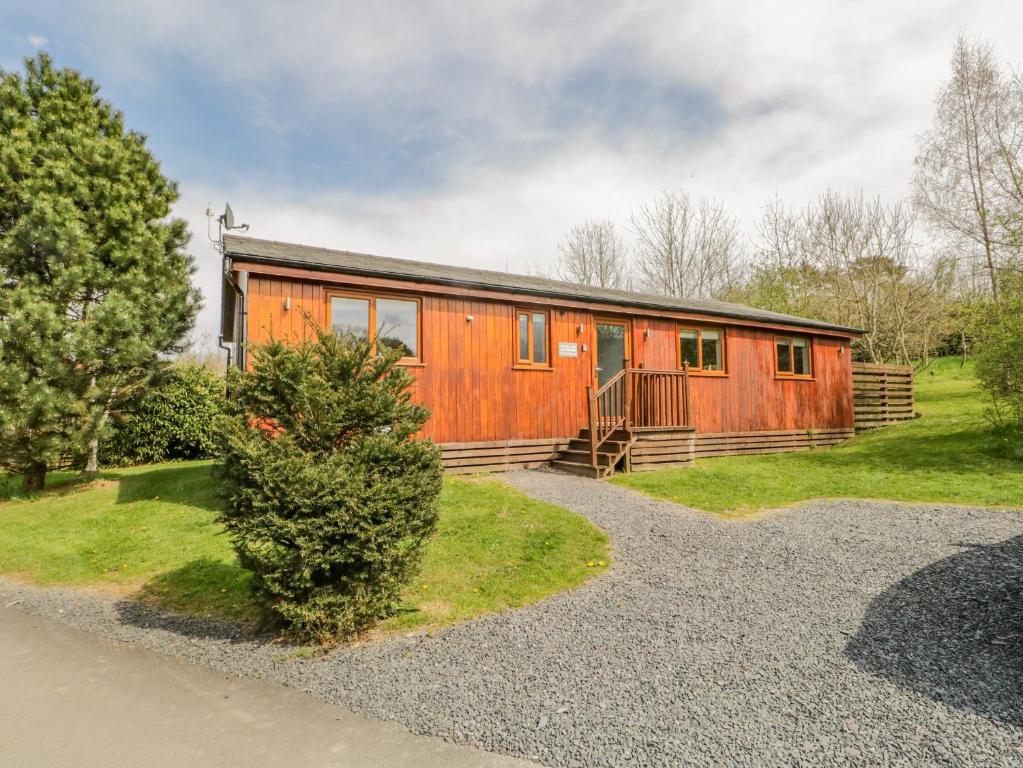 a large wooden house with a gravel driveway at Cartmel Lodge in Cartmel