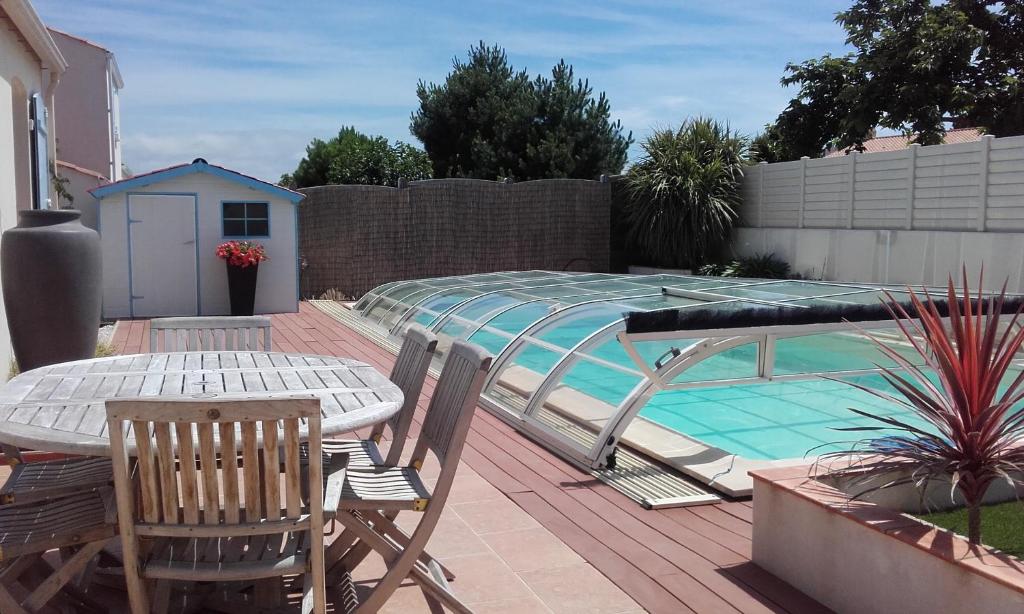 un patio con mesa y sillas junto a una piscina en Casa breti, en Bretignolles-sur-Mer