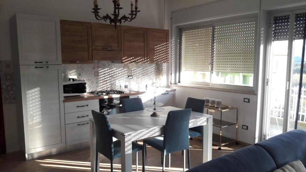 een keuken met een witte tafel en blauwe stoelen bij Pecciolo Port Apartaments in Milazzo