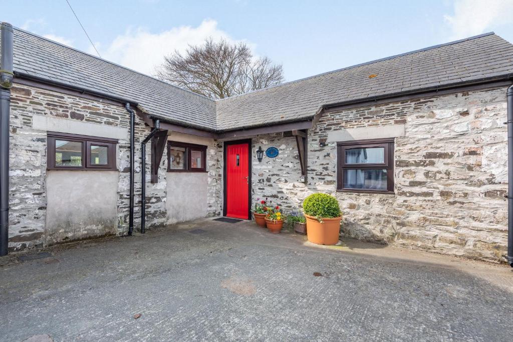 ein Backsteinhaus mit einer roten Tür davor in der Unterkunft Stables Cottage in Llanrwst