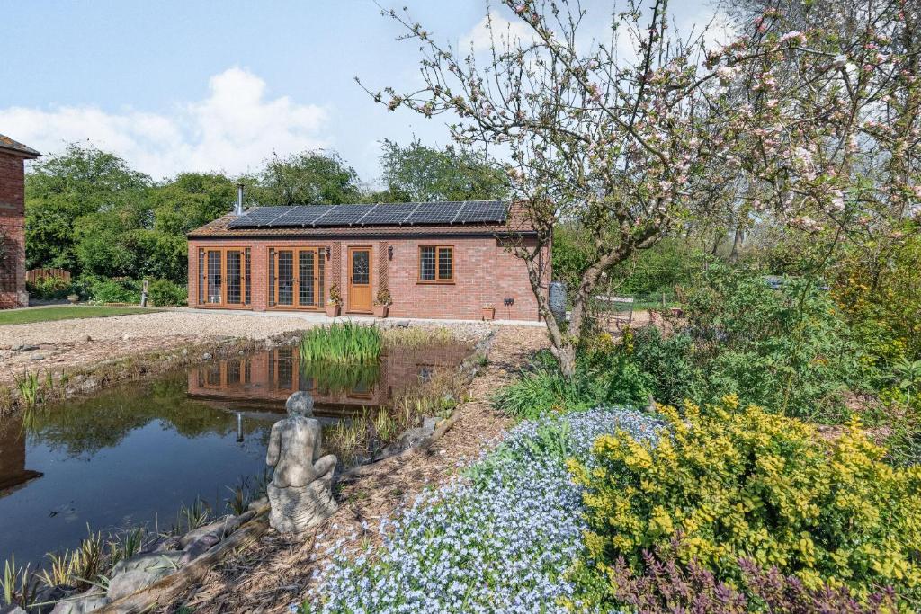 ein Haus mit Sonnenkollektoren auf dem Dach neben einem Teich in der Unterkunft Garden Cottage in Spilsby