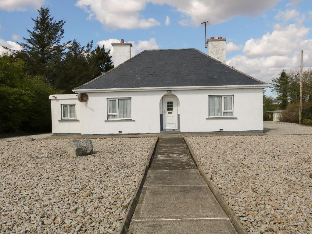 a white house with a gravel driveway at Carnmore Cottage in Dungloe