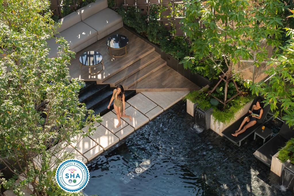 an overhead view of a swimming pool with people in the water at Gardina Asoke Hotel & Residence - SHA Certified in Bangkok