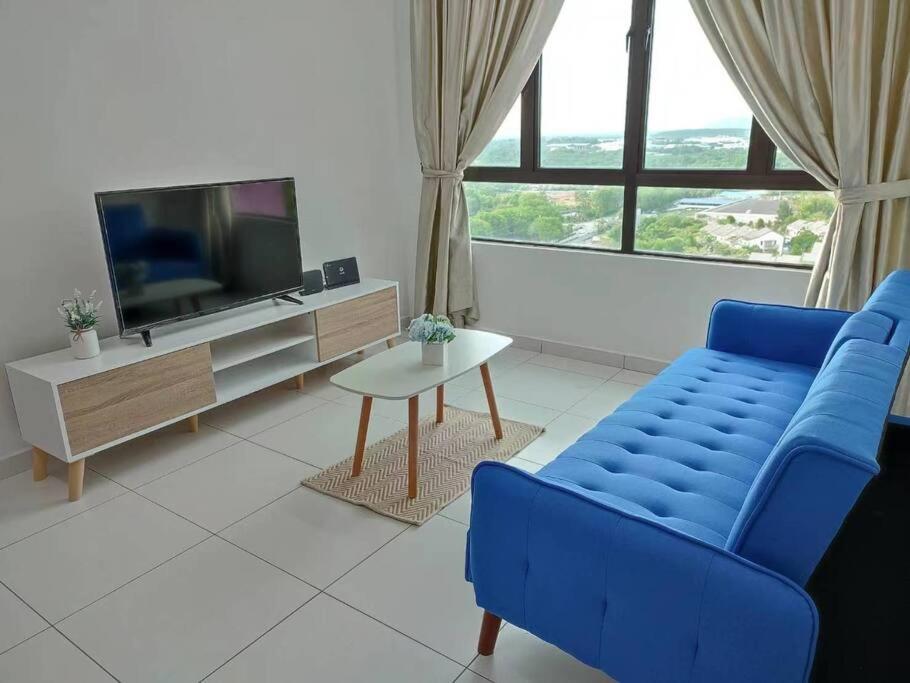 sala de estar con sofá azul y TV en Cozy Condo at Melaka Top Hill, 7-9pax, en Ayer Keroh
