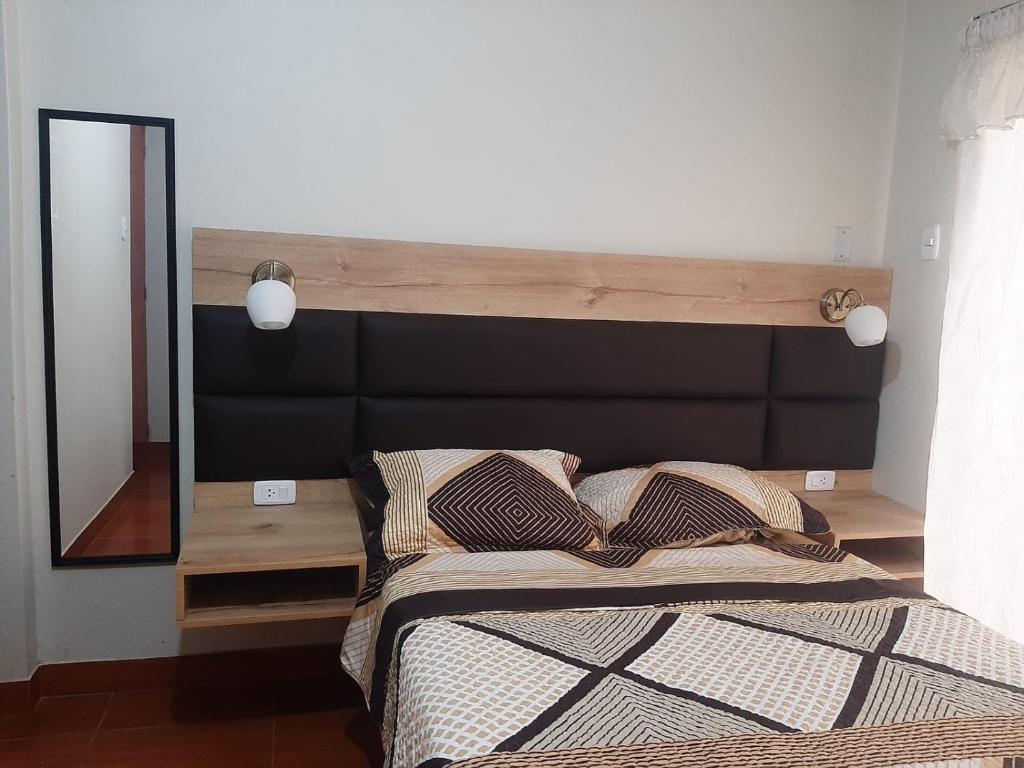 een bed met een groot houten hoofdeinde en een spiegel bij Hospedaje Costa Malabrigo in Puerto Chicama