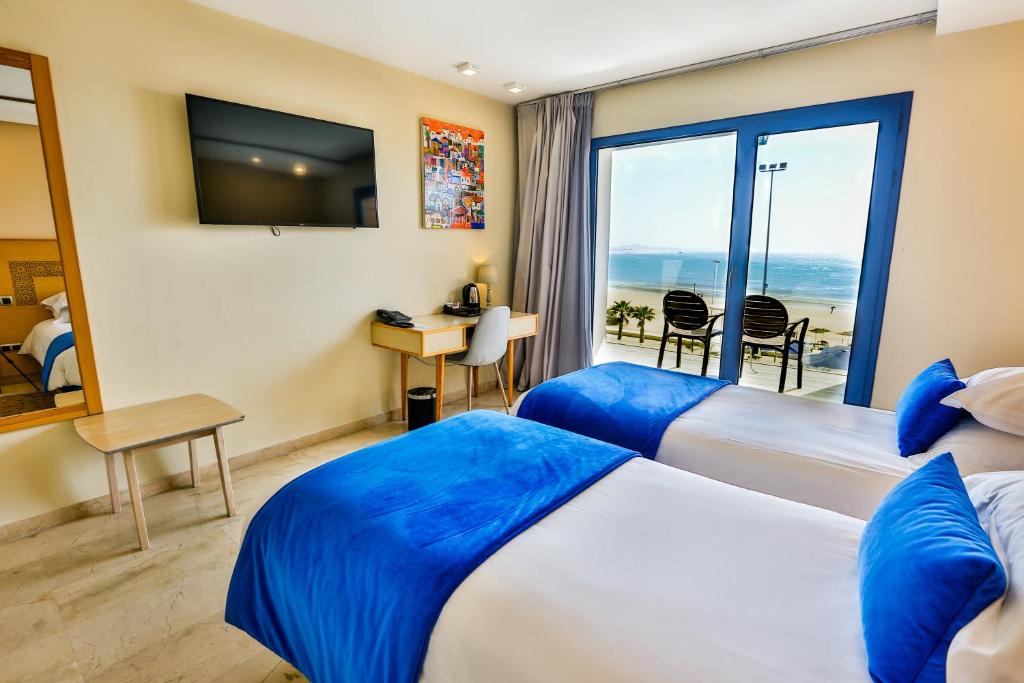 a hotel room with two beds and a view of the ocean at Hotel Cote ocean Mogador in Essaouira