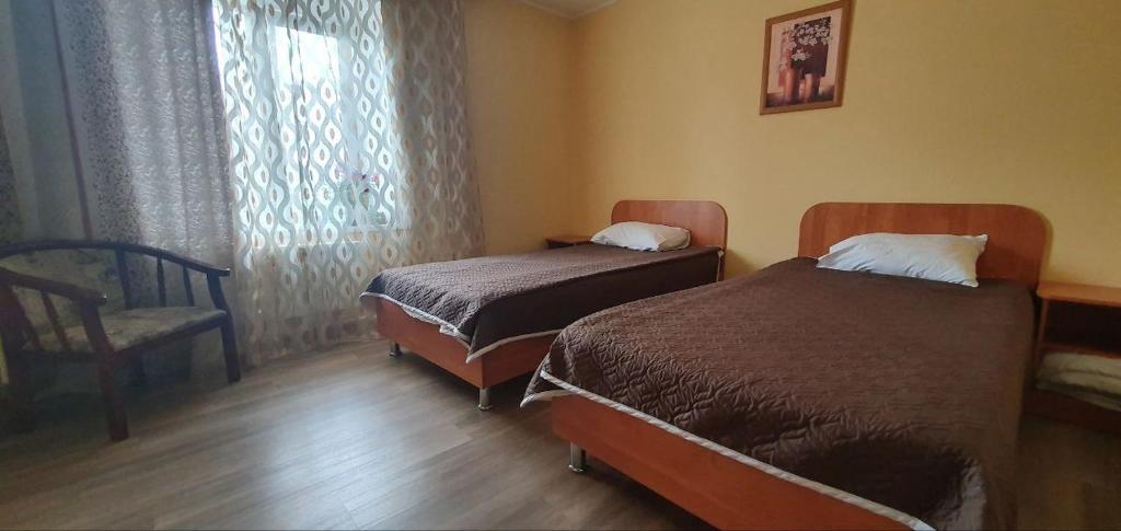 ハバロフスクにあるДОС Отельのベッド2台、椅子、窓が備わる客室です。