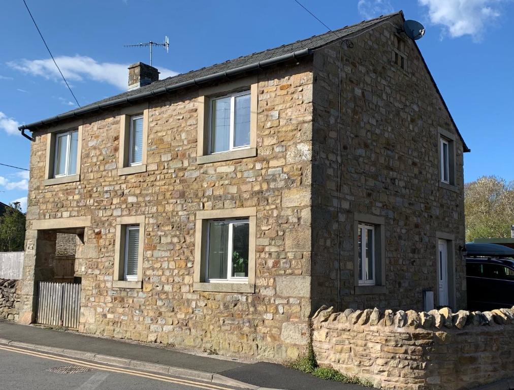 uma casa de pedra ao lado de uma rua em Dawsons Cottage em Lancaster