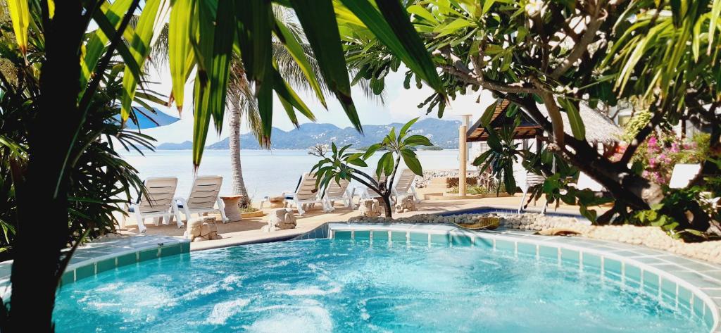 a swimming pool next to a beach with chairs at Papillon Resort in Chaweng