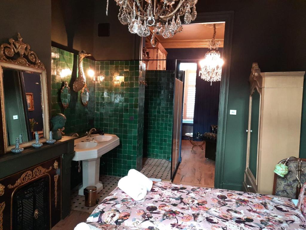 y baño con cama, lavabo y lámpara de araña. en Sint Andries Suites en Amberes