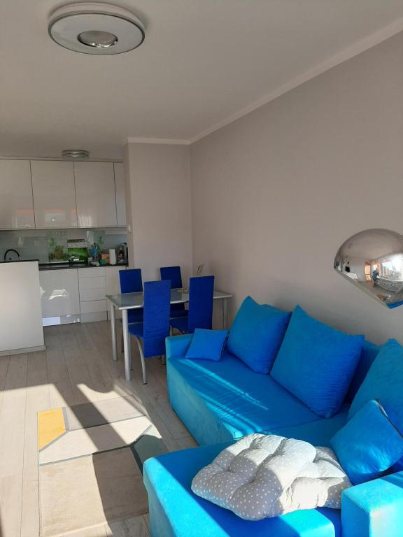 a living room with a blue couch and a kitchen at Apartament w Lądku Zdroju przy Rynku in Lądek-Zdrój