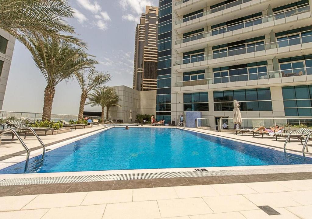 a swimming pool in front of a building with palm trees at Nasma Luxury Stays - Botanica Tower in Dubai