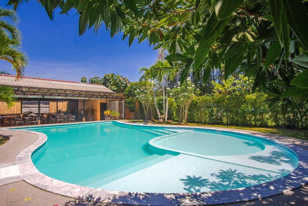 a swimming pool in front of a house with trees at Prayai Changthai Resort in Phuket Town