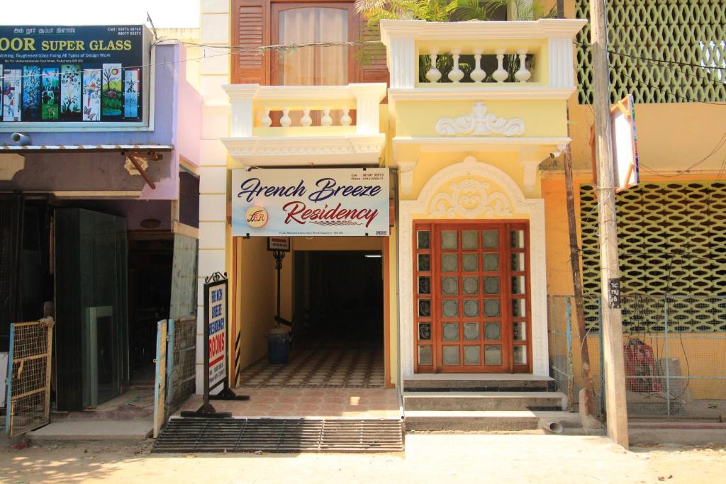 un bâtiment avec un panneau indiquant un restaurant et une porte rouge dans l'établissement French Breeze Residency, à Pondichéry