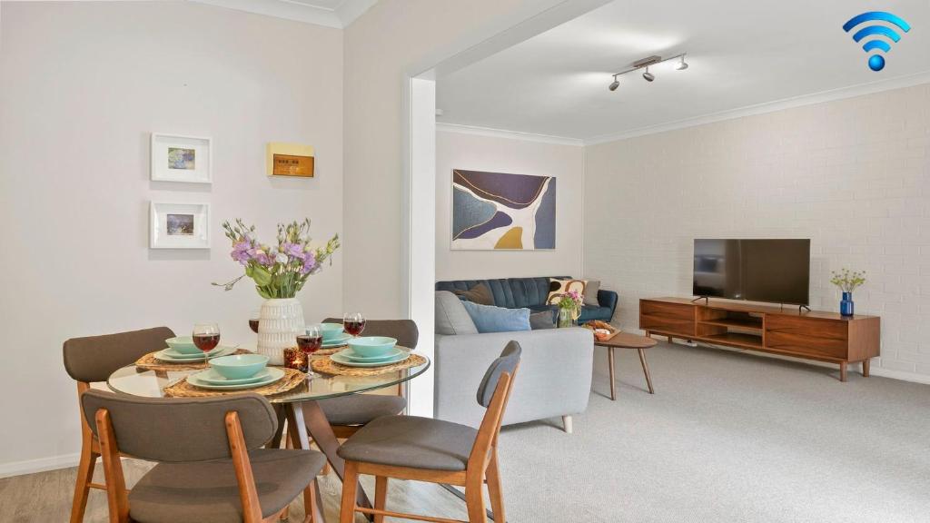 a living room with a table and chairs and a tv at Finchs Nest in Moss Vale