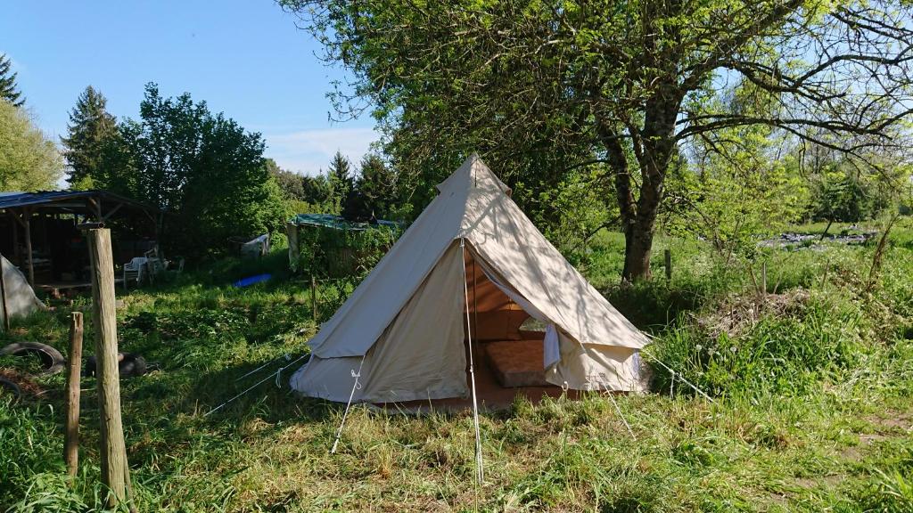 a white tent sitting in the grass in a field at Tente en permaculture pirate in Creysse