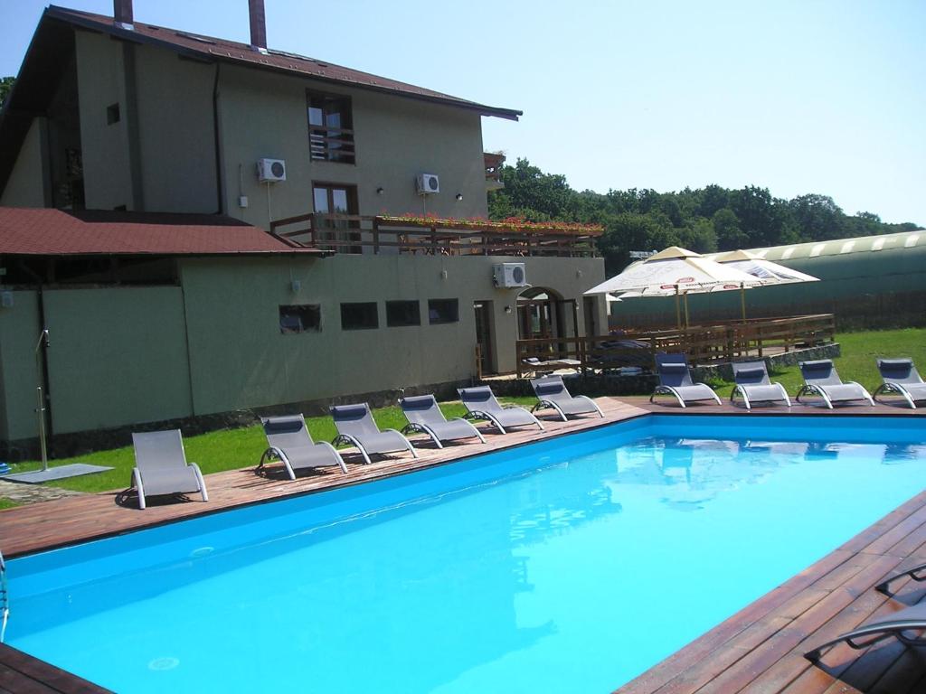 une piscine avec des chaises longues et un bâtiment dans l'établissement Pensiunea Larysse, à Băile Felix