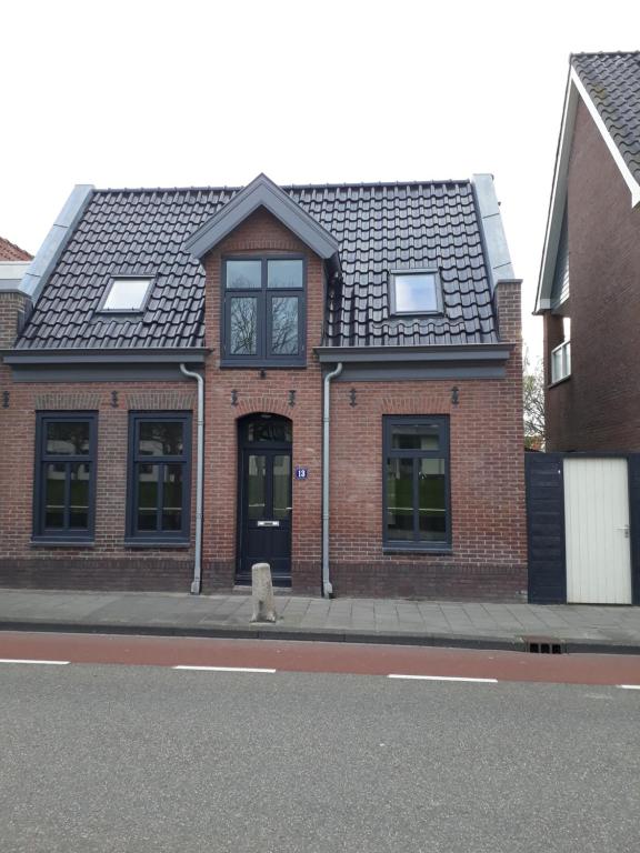 un edificio de ladrillo con un perro sentado frente a él en janneke, en Egmond aan Zee