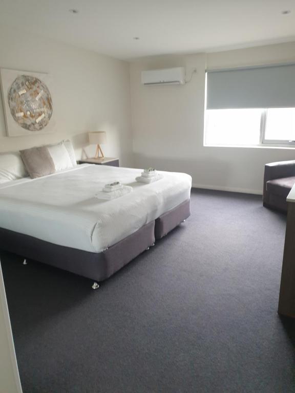古尔本Carlton Suites的白色卧室设有一张大床和一张沙发